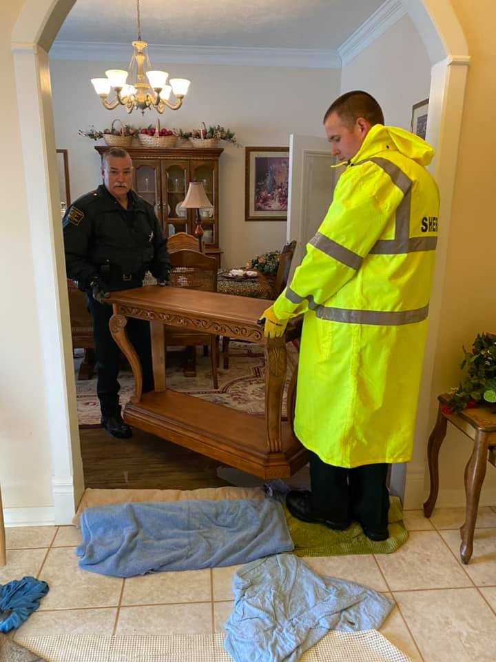 Detective Ethan Crockett and Patrol Supervisor Jason Horton removing furniture from the water soaked area of the home.