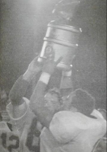 A pair of Pickering players hold up the original Big Dog Jug after winning the first game of the series in 2000.